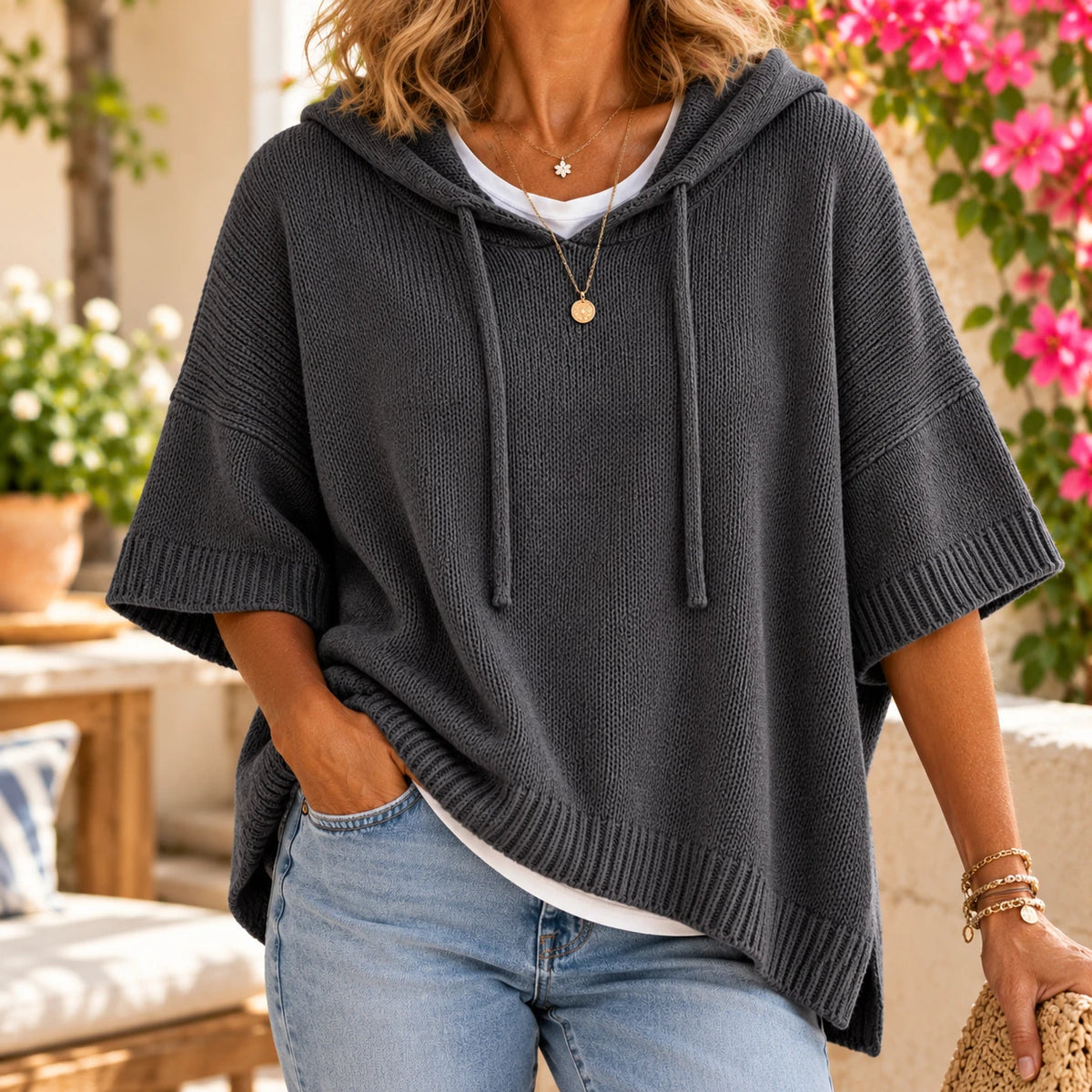 The poncho sweater in Charcoal — a drawstring hood and wide, flowing sleeves.
